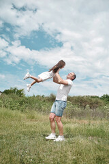 Fototapeta premium Dad and daughter have fun in the field . Happy family concept. Dad throws his daughter into the sky 