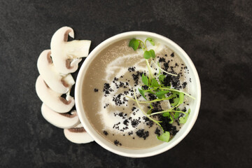 French cuisine hot food delivery - mushroom soup closeup in eco paper bowl  on black background. Delivery healthy eating concept.
