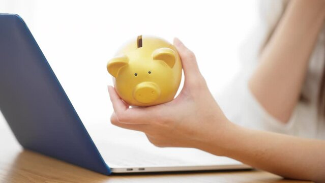 ブタの貯金箱を持つ若い女性