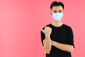 Young man in medical mask on pink background