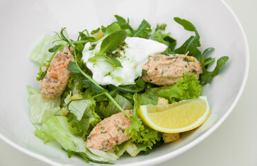 Diet vegetarian salad with greens, poached egg, lemon and fish fillet with dressing, the theme of proper and healthy nutrition and weight loss