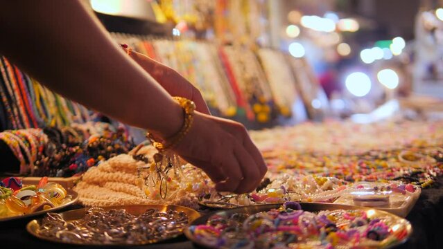 Tourist woman choosing necklace jewelry at night street market. 4K slowmotion close up footage. Phuket Town, Thailand.