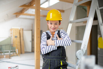 cool young boy with yellow safety helmet posing and having fun on construction building site indoor...