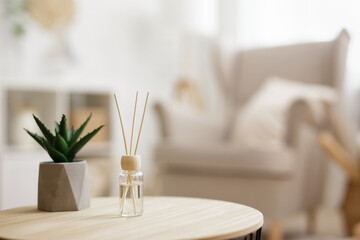 close up of reed diffuser and house plant aloe vera on wooden table in bright living room - obrazy, fototapety, plakaty