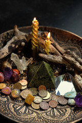 Witch altar with candles, different old coins, stone runes, crystals on dark table background close...
