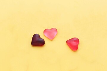 three voluminous, translucent hearts in pink tones on a yellow background