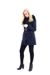 full length portrait of blonde woman wearing long winter coat. and casual clothes. standing pose, isolated on a white studio background.