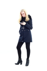 full length portrait of blonde woman wearing long winter coat. and casual clothes. standing pose, isolated on a white studio background.
