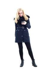 full length portrait of blonde woman wearing long winter coat. and casual clothes. standing pose, isolated on a white studio background.