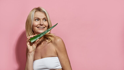 Woman holding aloe vera leaf and looking away