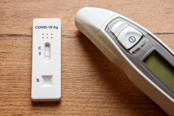 Positive Antigen Rapid Test for Coronavirus and Medical Thermometer.