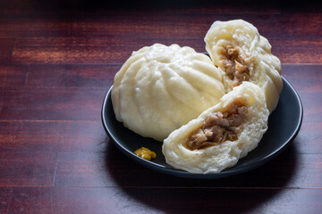 Steamed pork bun Nikuman, Chinese baozi on plate over wooden background, traditional Japanese food