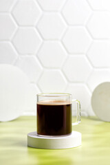 Glass coffee cup with espresso in morning on podium and green background. Aroma, ristretto. Mug of coffee.