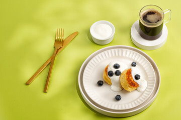 Breakfast with dessert and coffee in sunny day. Creative and minimalism. Green background. Gold tableware