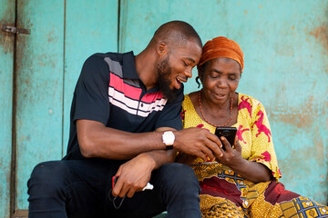 young black man assisting an elderly woman using her phone