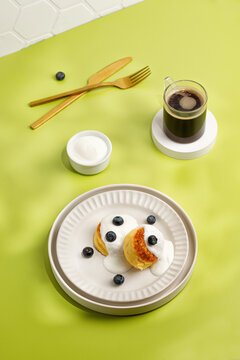 Still Life In Sunny Day, Breakfast Idea On Green Background. Dessert On Plate, Gold Tableware