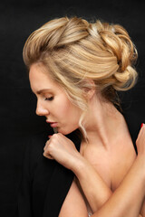 Beautiful model girl with an elegant hairstyle. Stylish woman. Portrait of a beautiful woman with blond hair. Black background.