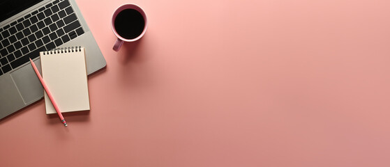 A top view of office utilities flat lays such as note books, laptop and a cup of coffee on an empty pink space on a background, for business and technology concept.