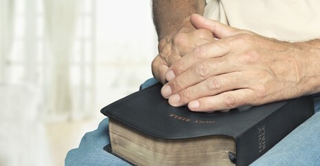 A religious human with Bible praying in room