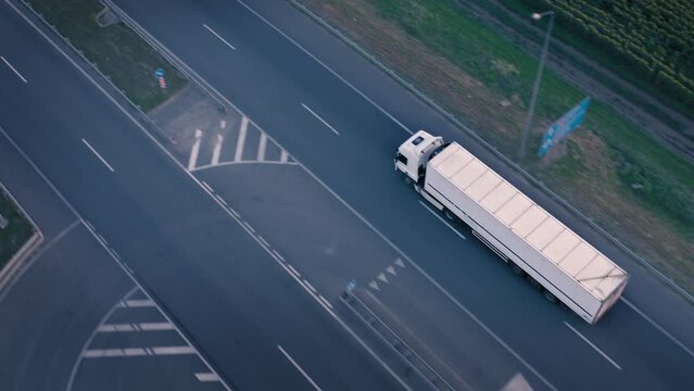 Moving white truck with semi-trailer on country road: transportation of commercial goods, transportation by truck: overhead drone tracking shot. White Shipping Truck moves to Logistic Warehouse center
