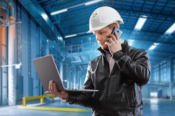 young successful engineer looks into the laptop and talks on the phone