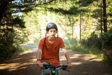 Obraz premium happy teen boy riding a bike on natural background, forest or park. healthy lifestyle, family day out