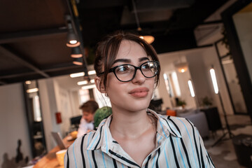 Portrait of businesswoman in casual clothes with glasses at modern startup open plan office interior. Selective focus 