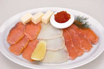 Fillet mix of red and white fish cut into slices with oil, red caviar and lemon, restaurant serving