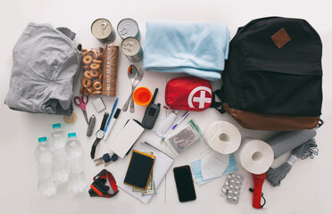 Emergency backpack equipment organized on the table. Documents, water,food, first aid kit and...