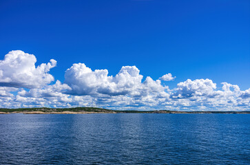 Skerries and coastline under a bright cloudy blue sky in the Koster fjord between the Koster...