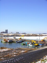 早春の江戸川浚渫工事現場と雪解けの河川敷風景