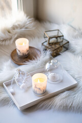 Fototapeta na wymiar Cozy home decor with faux fur blanket, burning candles and interior decorations