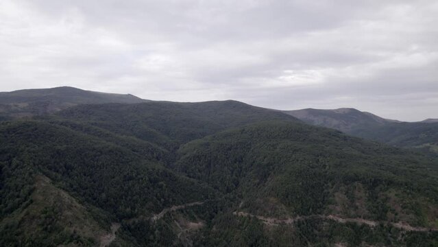 "golden hour" head-on drone video moving over the mountains of SH22 in albania, above the road on top of the hill. Cloudy sky.