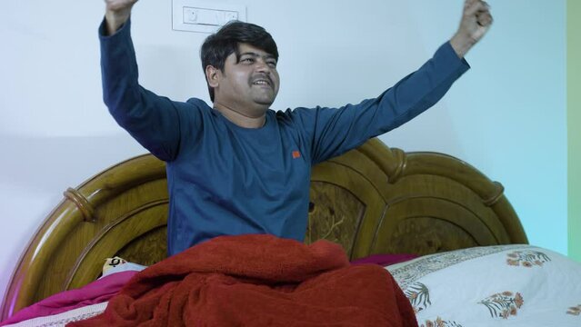 excited young man celebrating match win by shouting while watching match at bedroom during night - concept of entertainment, supporter and late nigh sports watching.