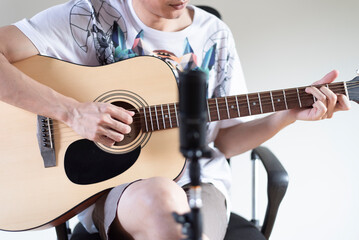 Musician playing acoustic guitar through front microphone, Cover singing concept, Close up.