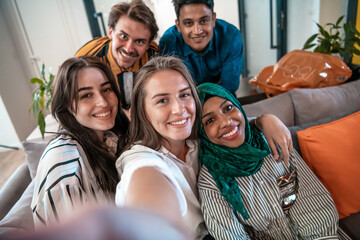 Group of business people during break from the work taking selfie picture while enjoying free time in relaxation area at modern open plan startup office. Selective focus 