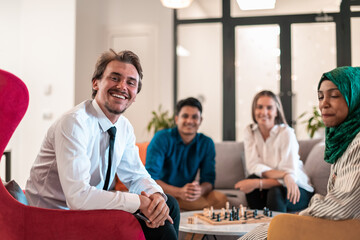 Multiethnic group of business people playing chess while having a break in relaxation area at modern startup office.