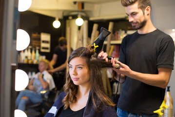 Young woman getting new hairstyle from hairdresser in the modern hair salon.