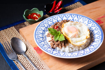 Thai Food concept Khao pad krapow rice and minced beef Thai holy basil stir-fry with fried egg in thai style ceramic plate with copy space