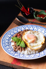 Thai Food concept Khao pad krapow rice and minced beef Thai holy basil stir-fry with fried egg in thai style ceramic plate with copy space