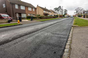 A newly resurfaced road with fresh tarmac laid on top of the existing road surface in Reading, UK.