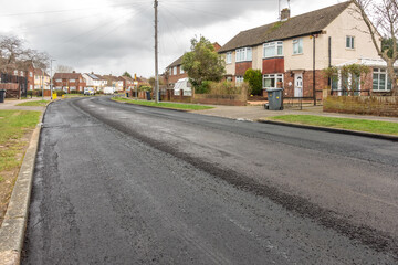 A newly resurfaced road with fresh tarmac laid on top of the existing road surface in Reading, UK.