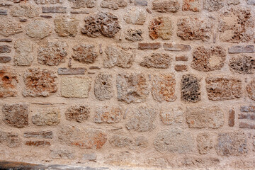 Old masonry from blocks of different sizes in cement mortar. Horizontal photo.