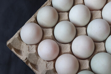 Close-up of egg whites in gray paper tray, on black background. top view.