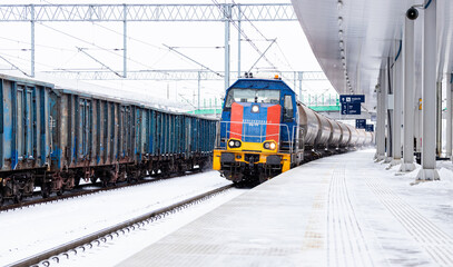 Pociąg transportowy przejeżdżający na stacji kolejowej zimą © PhotoHunter