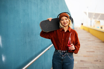 Fashion woman with skateboard. Urban woman listening the music.