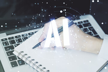 Creative artificial Intelligence symbol concept with hand writing in notebook on background with laptop. Multiexposure