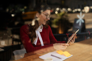 Beautiful young woman using digital tablet in cafe. Happy smiling woman enjoy in fresh coffee.