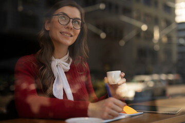 Beautiful young woman using digital tablet in cafe. Happy smiling woman enjoy in fresh coffee.