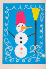 Children's Christmas paper crafts. Application of children's creativity. Kindergarten and craft school. On a beige background, a snowman made of colored paper.